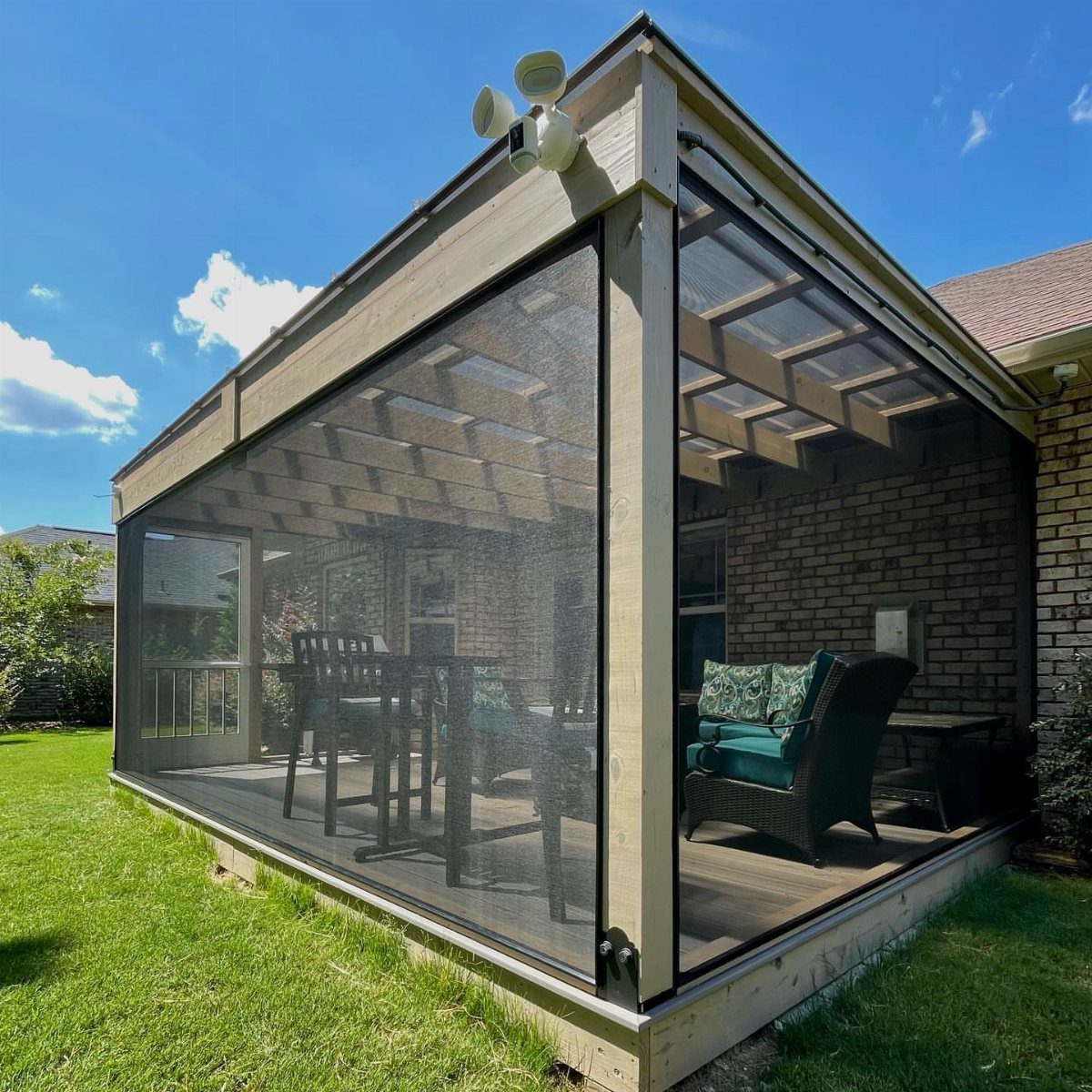 A screened-in wooden porch deck containing outdoor dining furniture and a lounge chair.