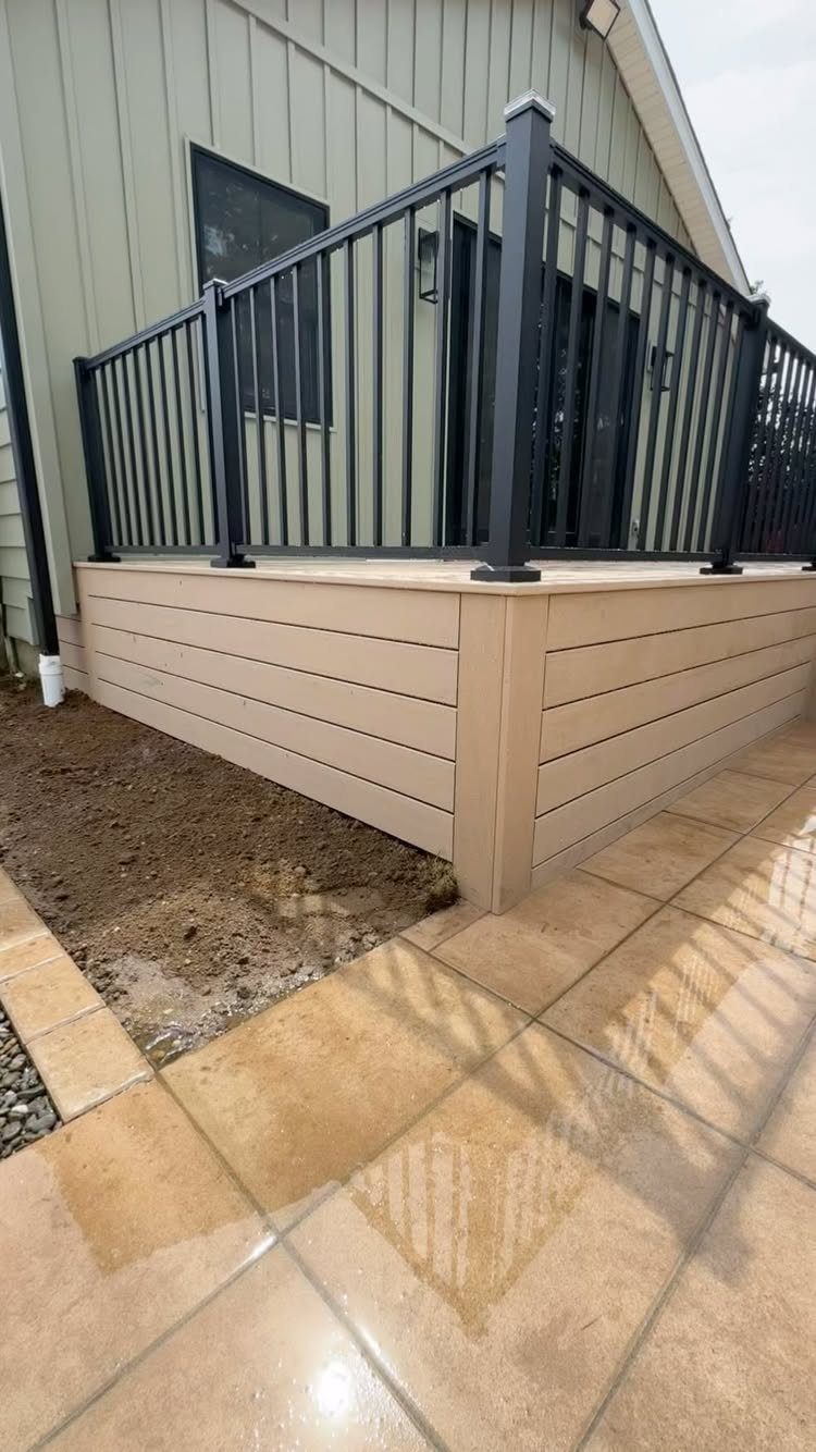 Black metal railing with vertical balusters installed on a tan composite deck base.