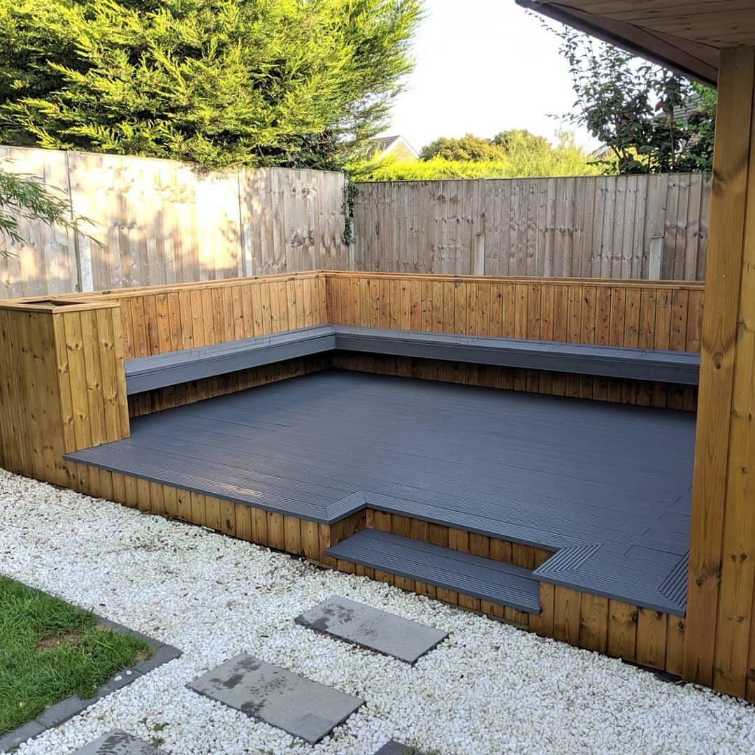 Anthracite gray composite decking boards with built-in gray benches on a wooden raised platform.