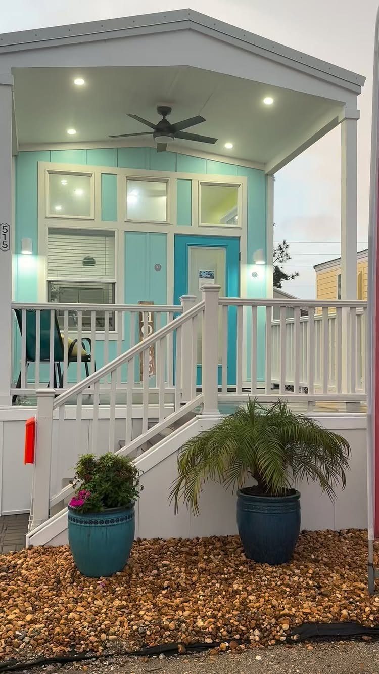 A small aqua blue cottage house with white trim and a covered porch area.
