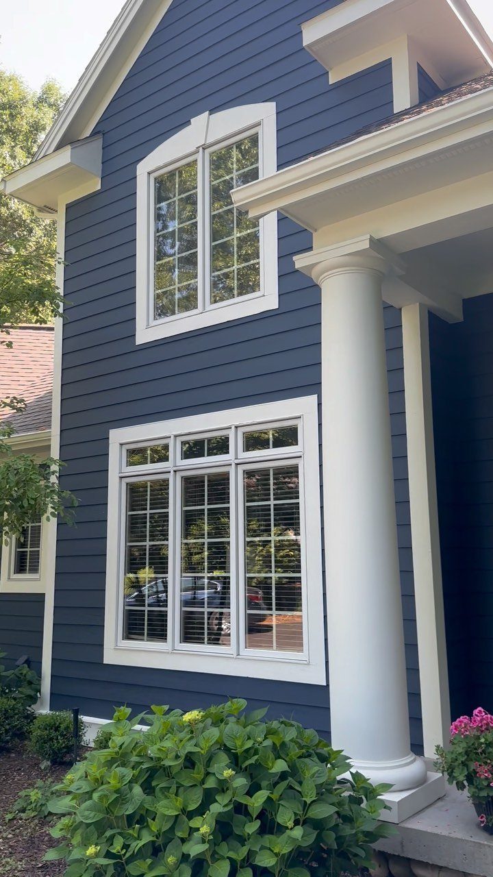 12 Trending House Colors for Exterior Looks in 2026 9 Blue house exterior with white window frames, white siding, and a large white column.