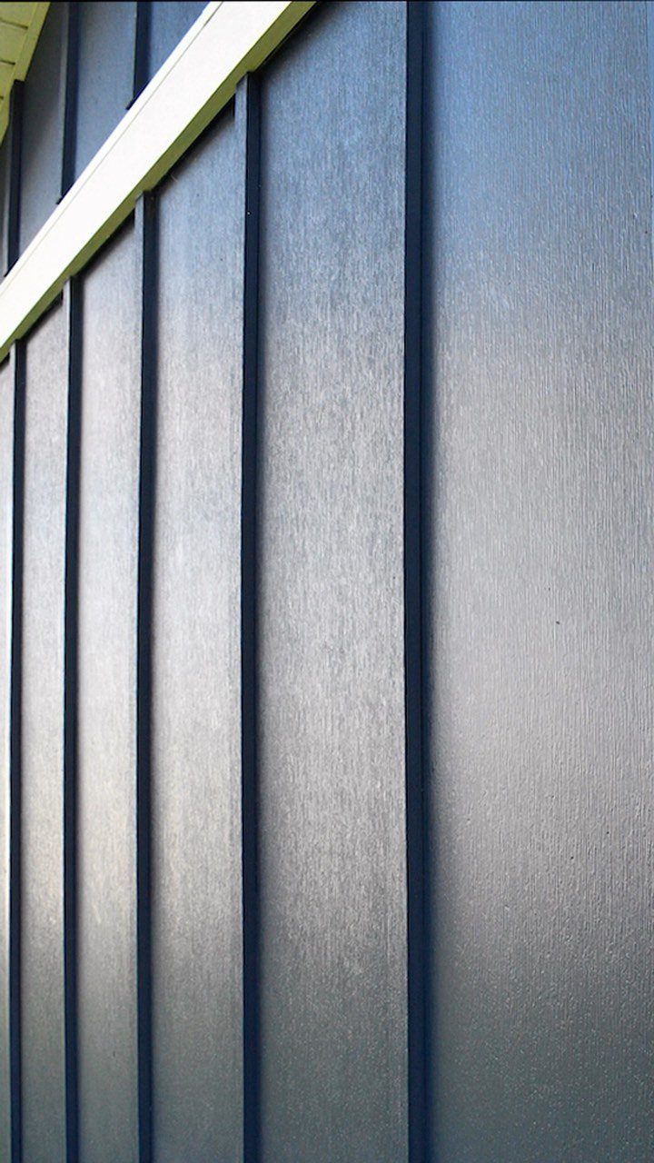 Dark gray vertical board and batten siding with white trim on an exterior wall.