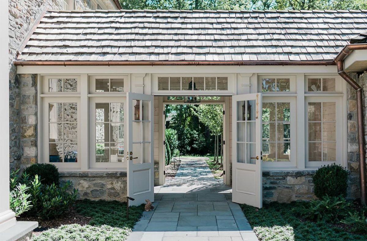 A stone building with white windows and open doors forming a covered breezeway.
