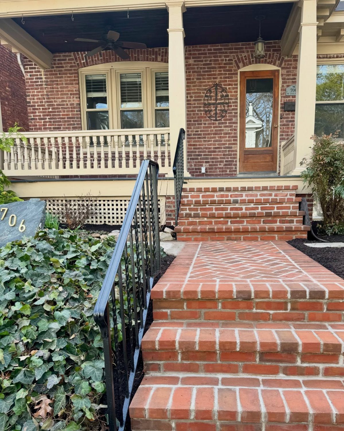 Red brick steps and walkway leading up to a brick front porch of a house.