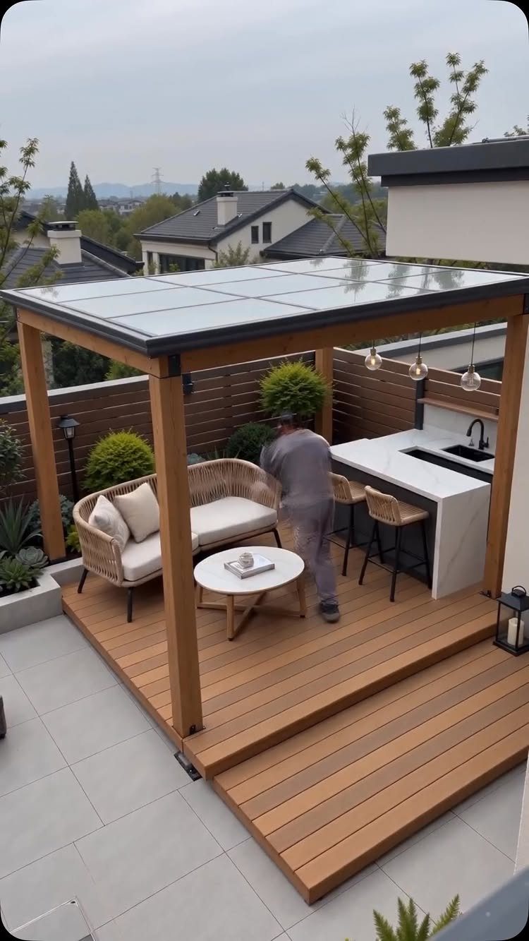 12 Deck with Gazebo Ideas for Outdoor Dining and Relaxation 6 A modern wooden deck featuring a glass-roofed gazebo with an outdoor kitchen and lounge seating.