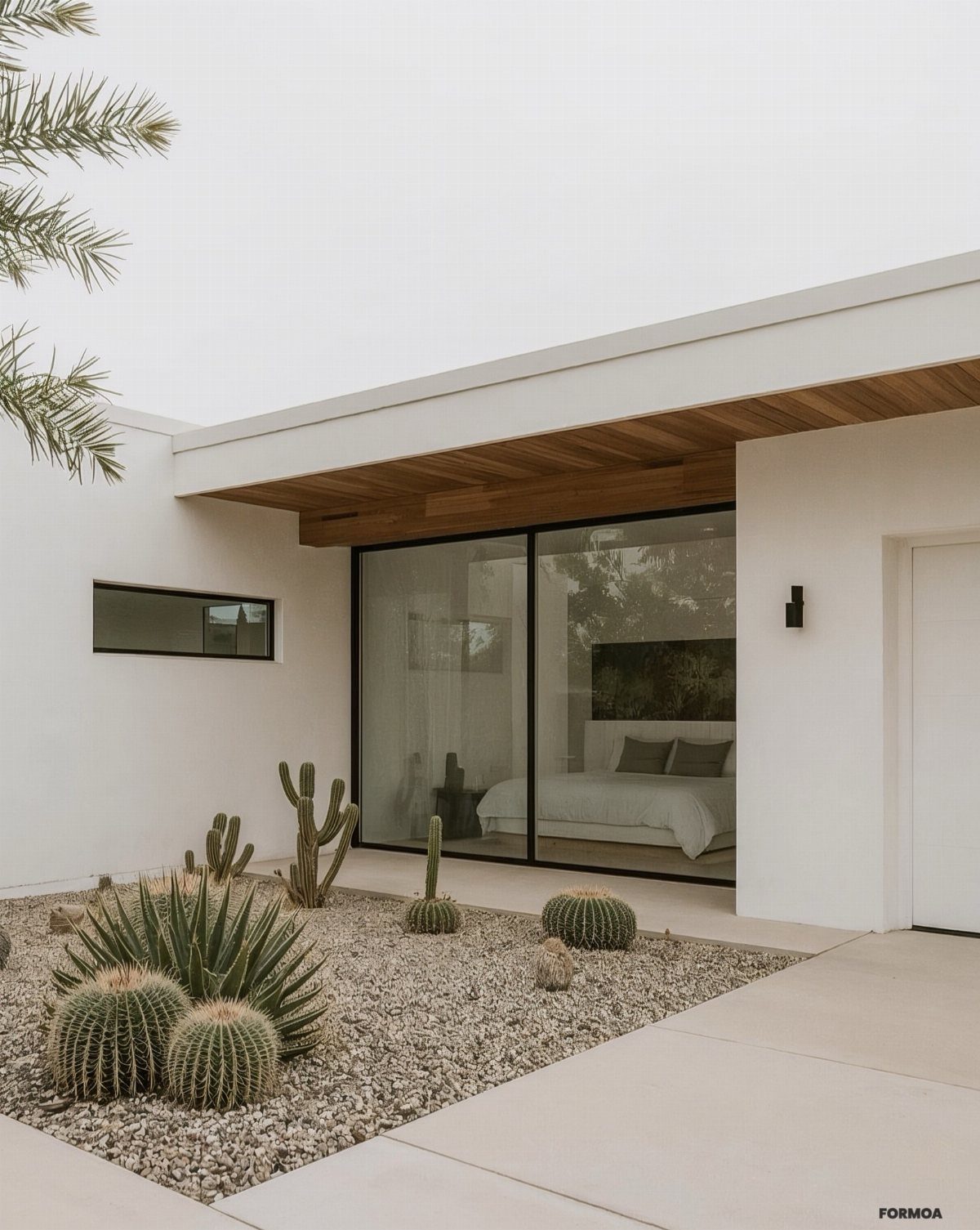 Cacti and succulents planted in a courtyard covered with light crushed gravel next to a modern house.