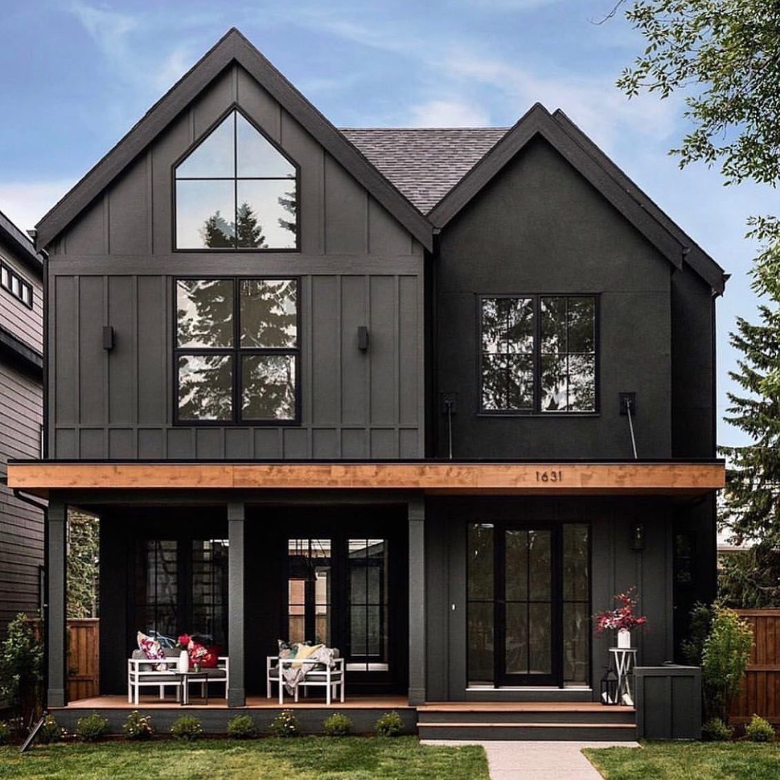12 Trending House Colors for Exterior Looks in 2026 4 A modern two-story house featuring dark charcoal exterior siding and large black-framed windows.