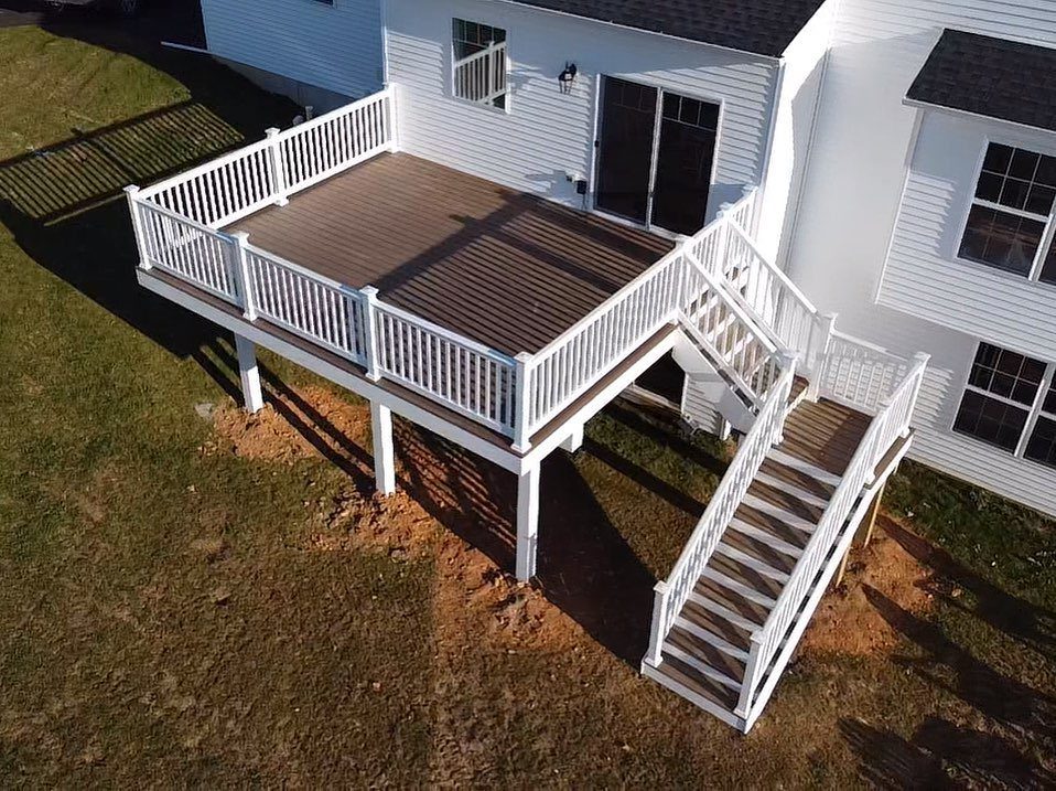 An aerial view of a wooden deck with white railings and white-wrapped support posts.