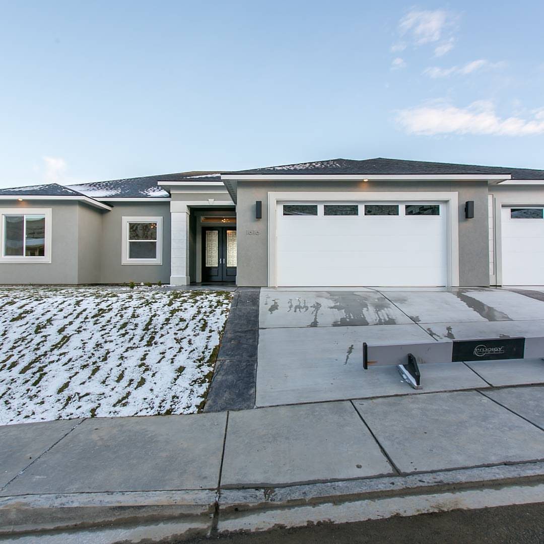 12 Trending House Colors for Exterior Looks in 2026 3 A modern single-story house featuring light gray exterior walls and white trim under a blue sky.