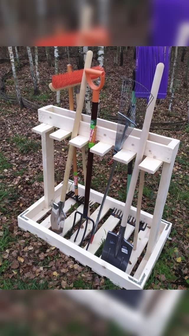 9 Shed Yard Tool Storage Ideas for Every Wall and Corner 8 A wooden garden tool organizer holding a shovel, pitchfork, and rake on a bed of leaves.