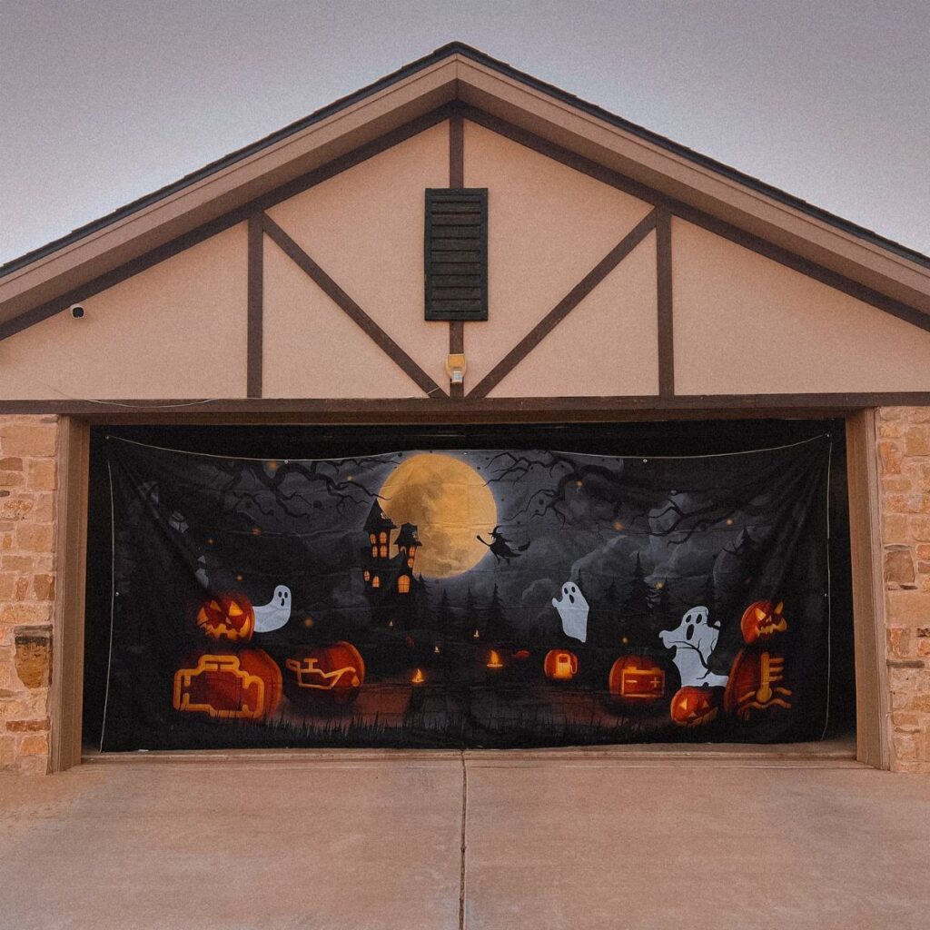 A Halloween themed banner with ghosts and pumpkins hanging over a garage door.