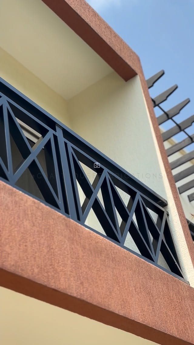 14 Deck Balustrade Ideas for Every Style, from Glass to Stone 5 Black metal railing with a geometric diagonal pattern on a balcony ledge.