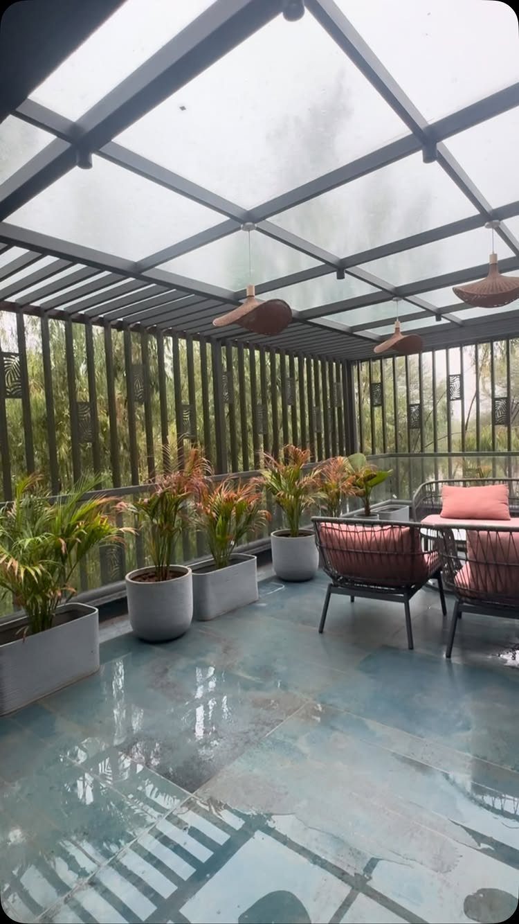 A modern patio featuring a translucent glass overhang, potted plants, and outdoor lounge furniture.
