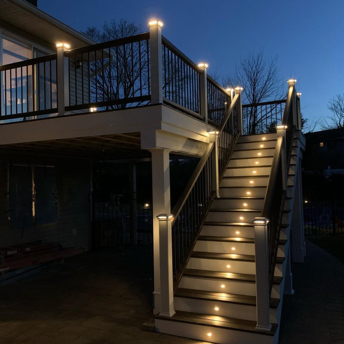 17 Beach House Deck Ideas for Oceanfront Living 12 A wooden deck with integrated lights on the stairs and posts at dusk.