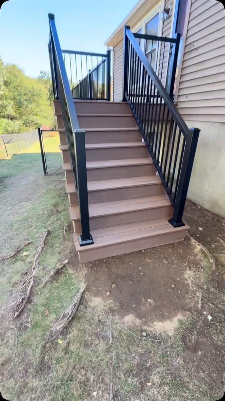 14 Deck Balustrade Ideas for Every Style, from Glass to Stone 3 Brown composite deck stairs with black metal railing leading up to a house.