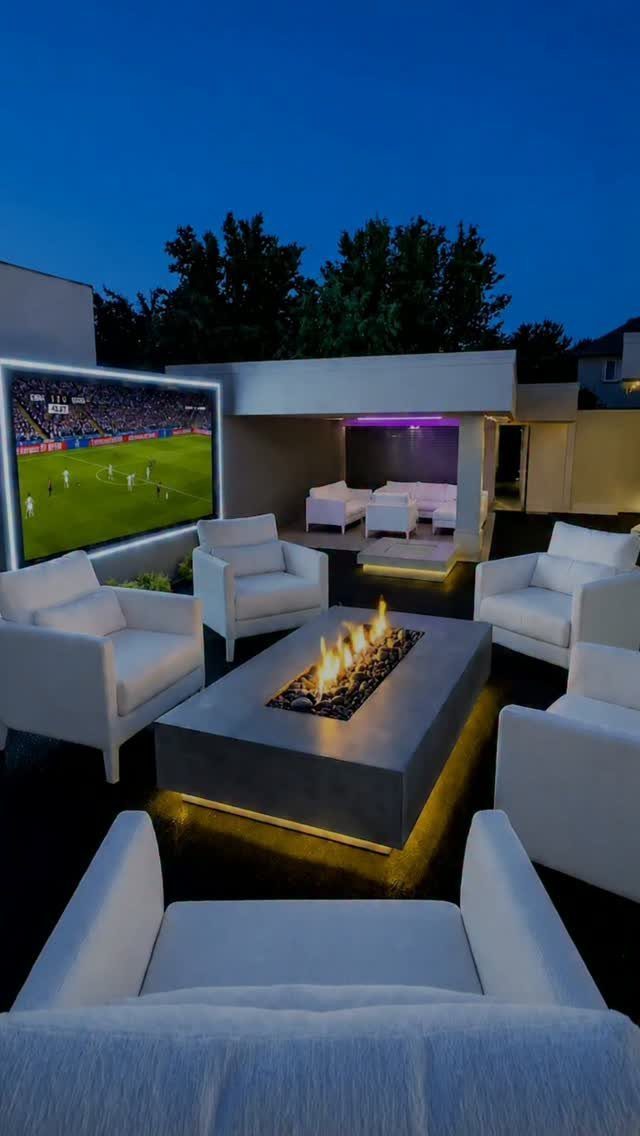 A rectangular concrete fire table with dancing flames surrounded by white modern outdoor armchairs.