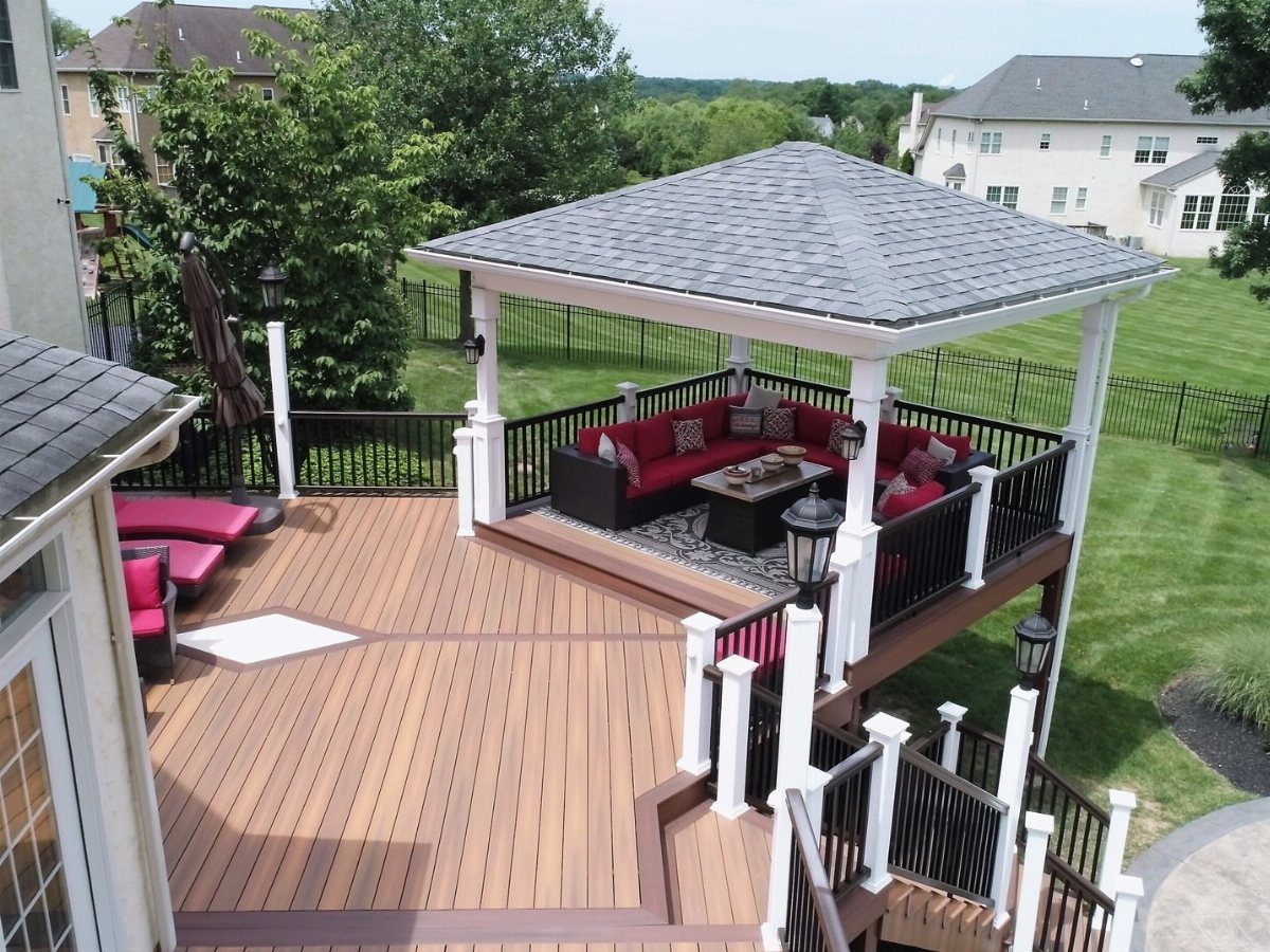 12 Deck with Gazebo Ideas for Outdoor Dining and Relaxation 10 A multi-level wooden deck with a large gazebo, red outdoor furniture, and white railings.