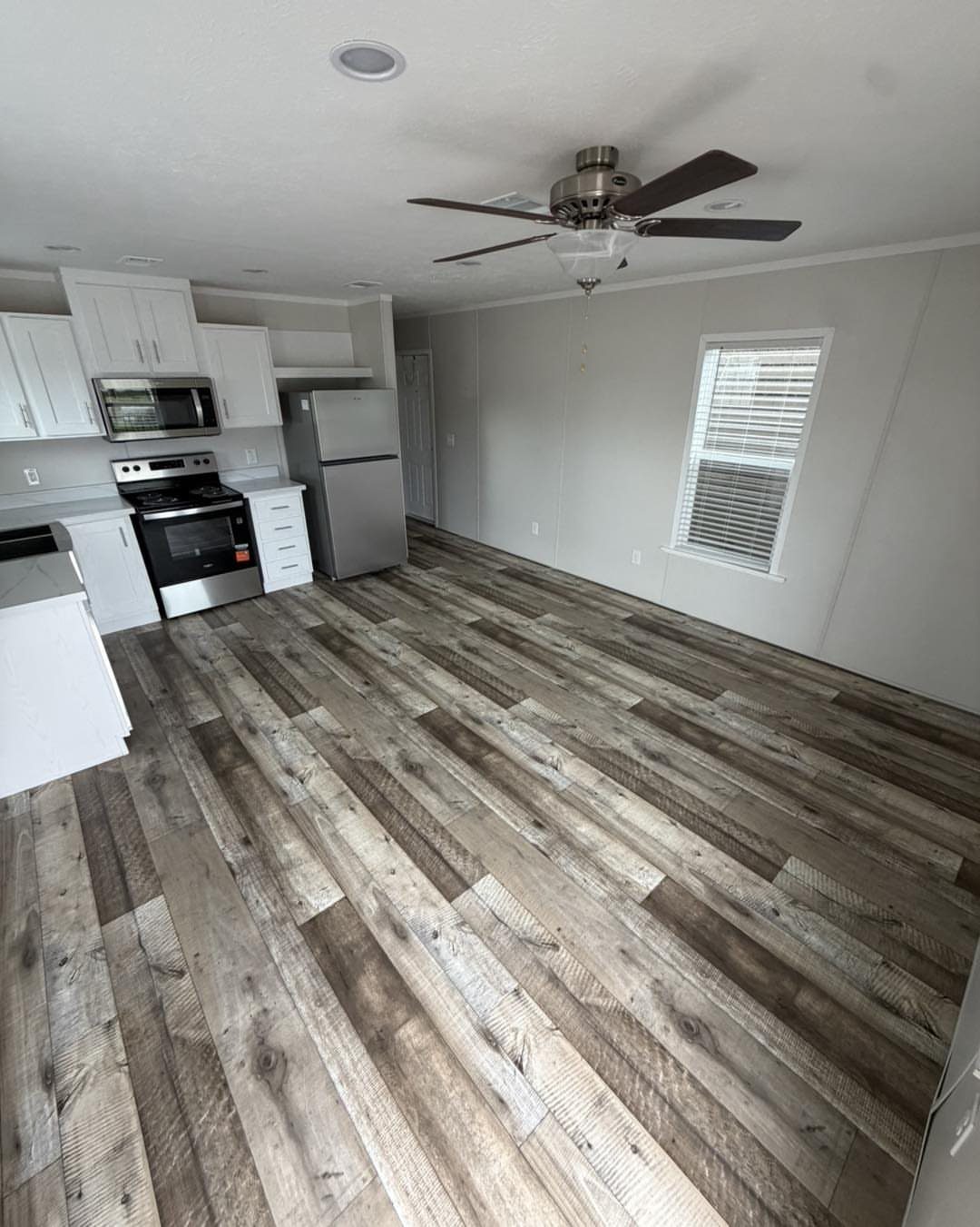 Interior view of a modern open-concept room with wood flooring, grey walls, and a small kitchen.