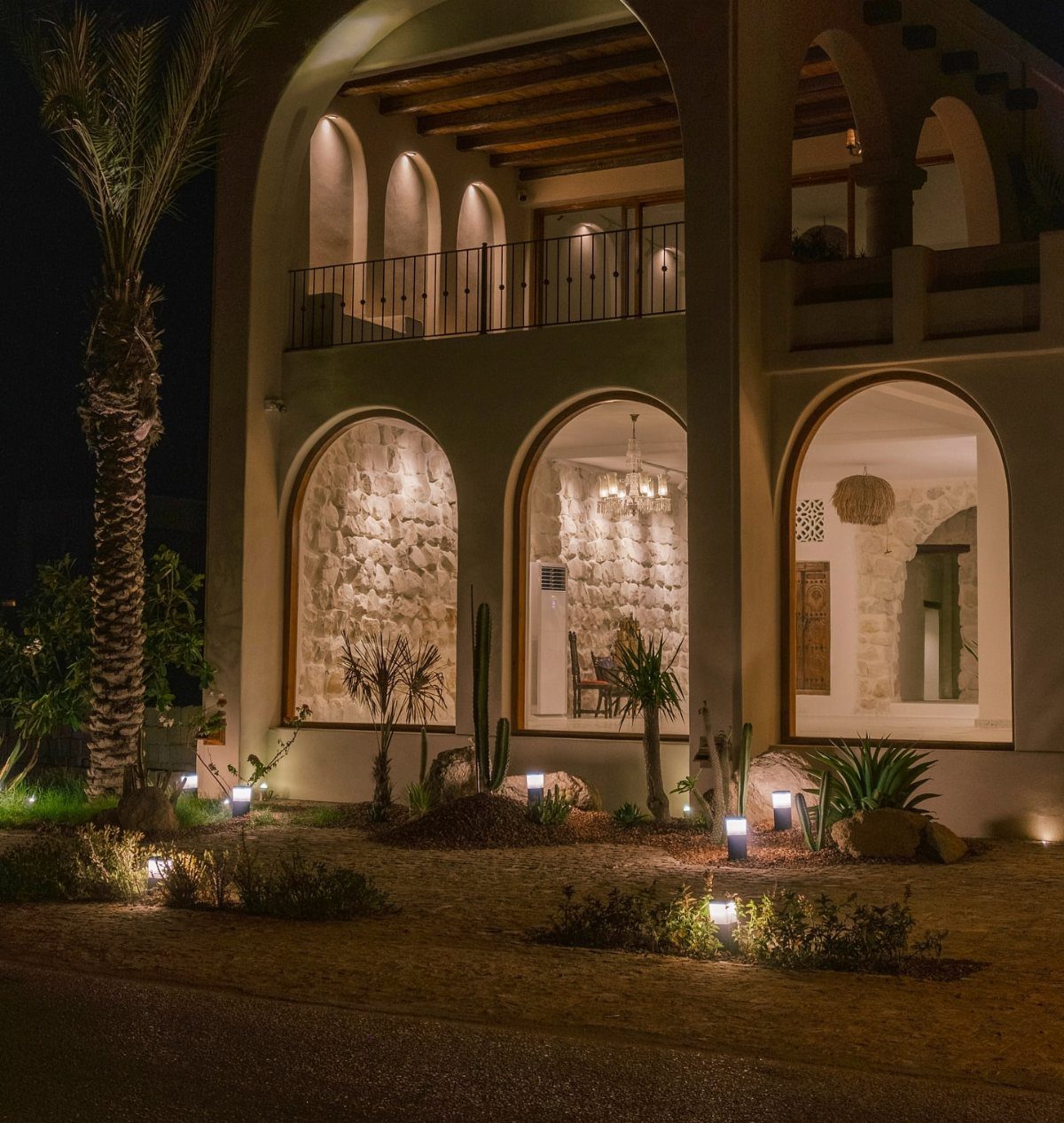 Modern bollard lights illuminating a desert landscape in front of a large arched home.