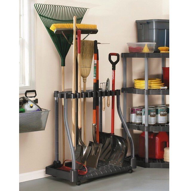 A grey wheeled tool storage rack holding various garden tools like rakes, brooms, and shovels.