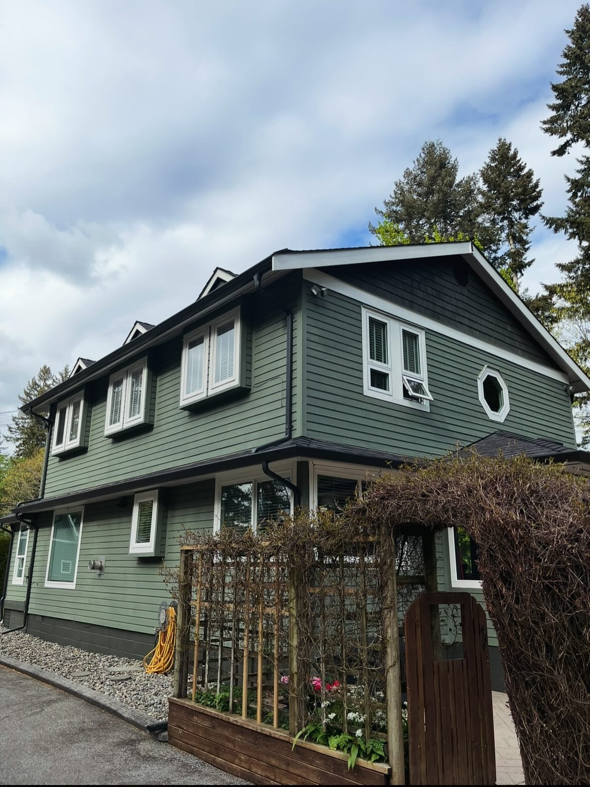A two-story house featuring sage green horizontal lap siding and white window frames.