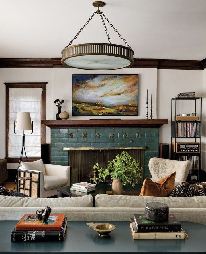 A living room with a teal tiled fireplace, dark wood trim, and a large circular brass light fixture.