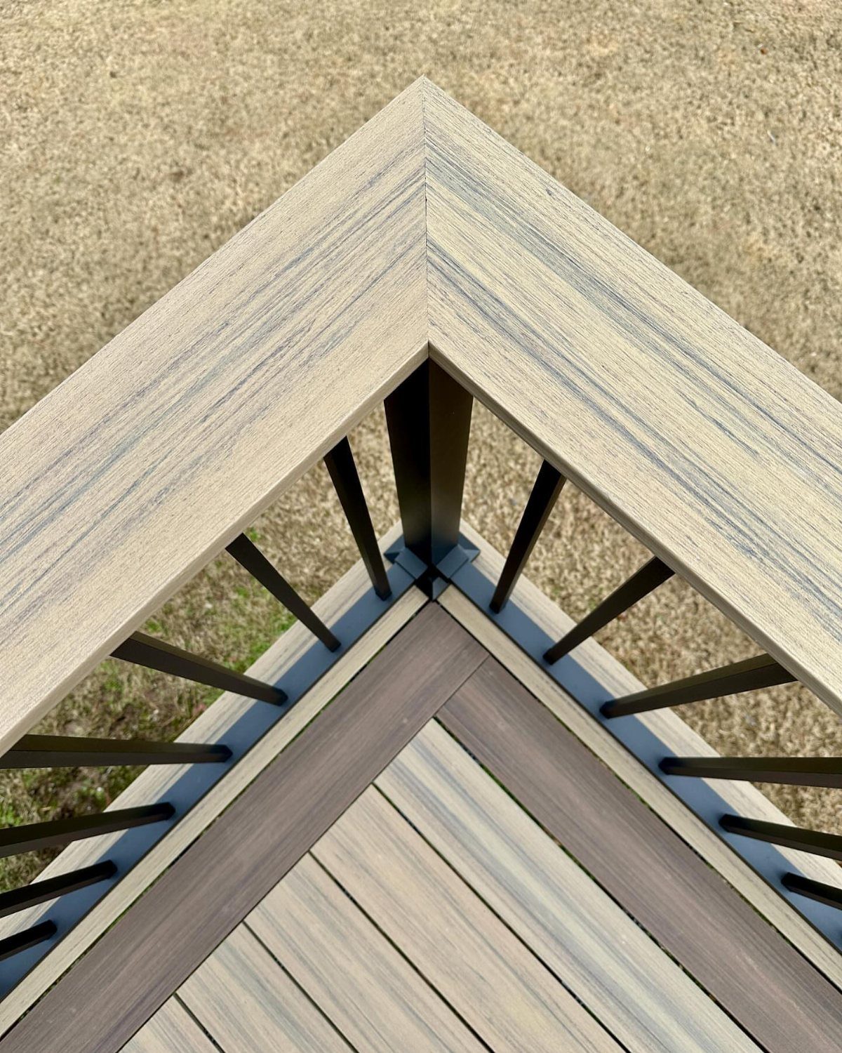 14 Deck Balustrade Ideas for Every Style, from Glass to Stone 7 A corner of a deck showing light grey composite railing with black metal balusters.