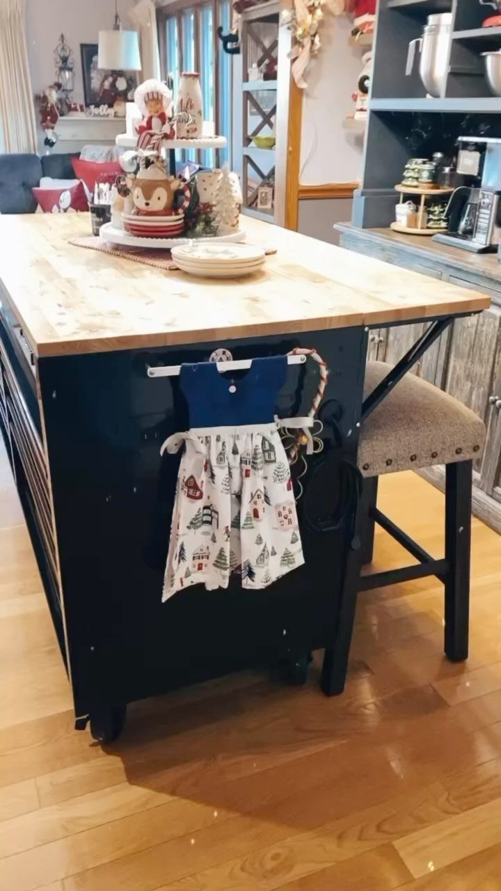 A dark blue kitchen island with a butcher block countertop and a hanging apron.