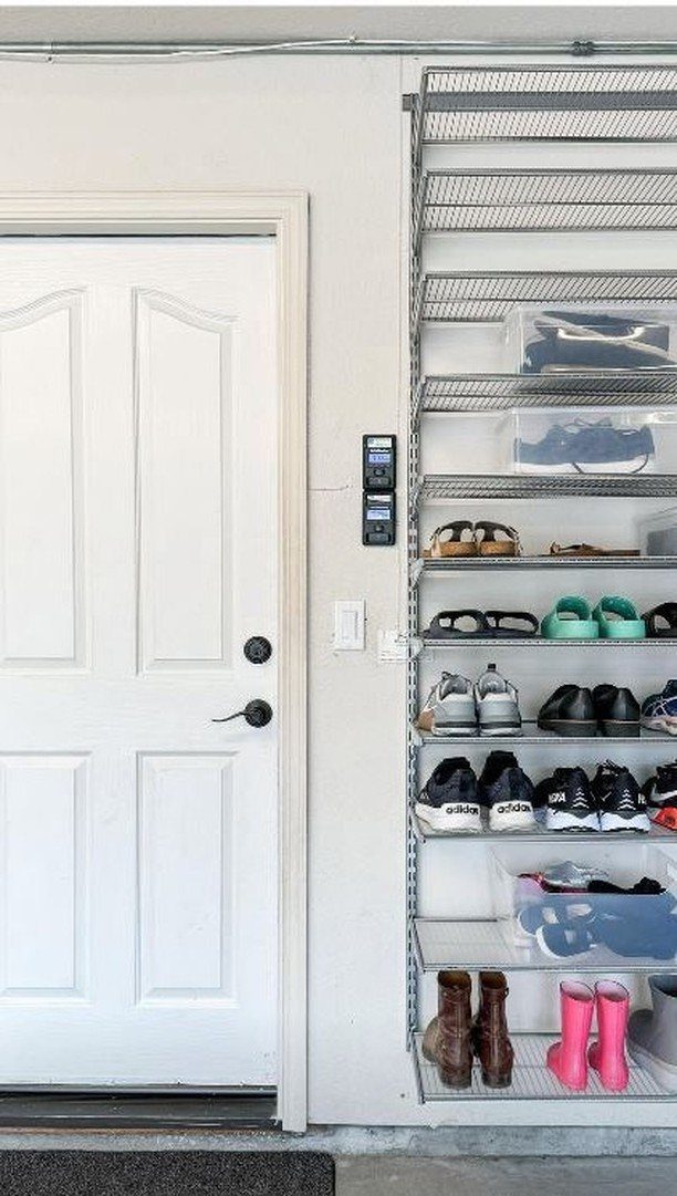 A white door next to a metal wire shelf organized with many pairs of shoes.