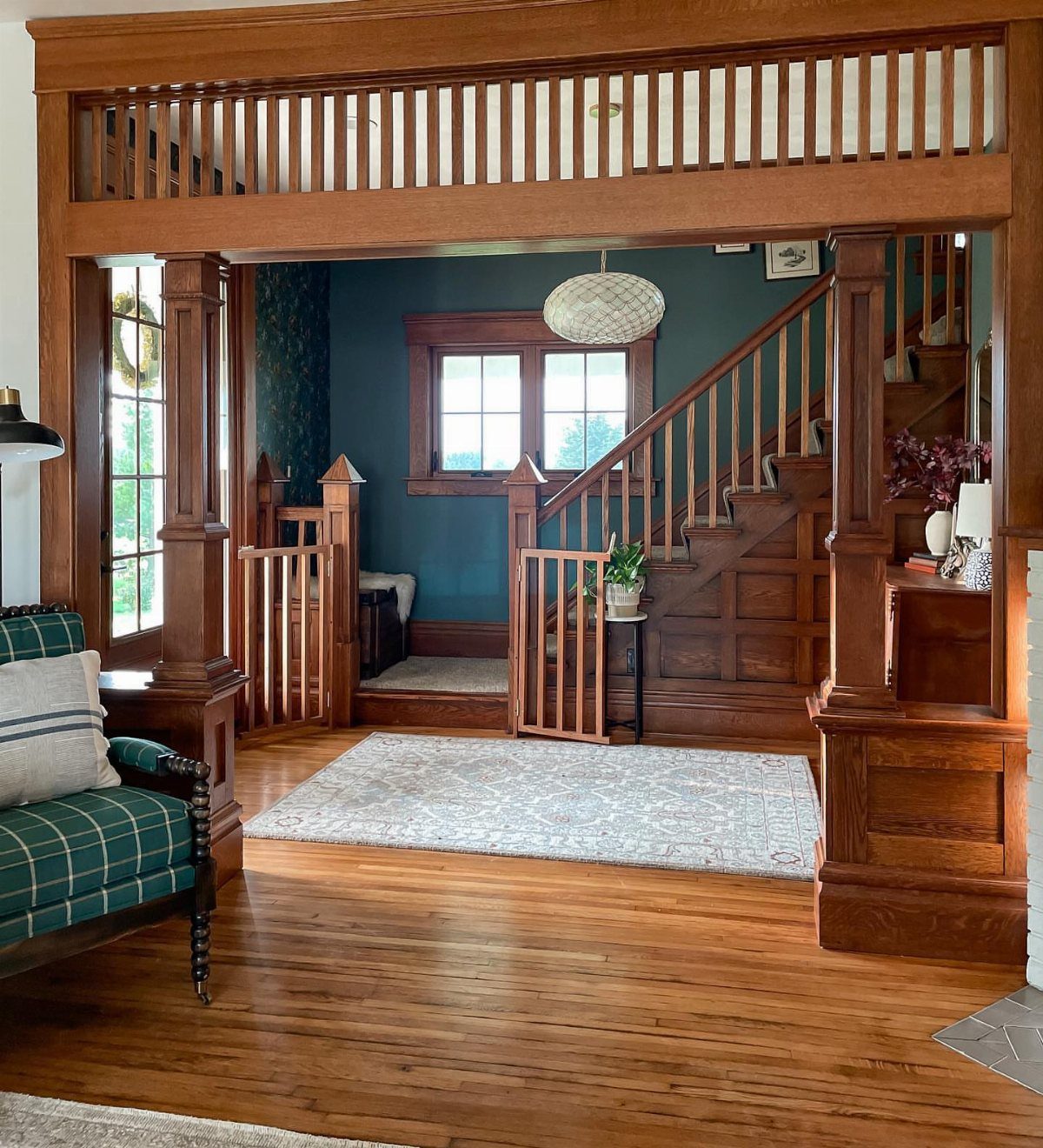 Craftsman style interior with dark wood paneling, a staircase, and teal walls in a living area.
